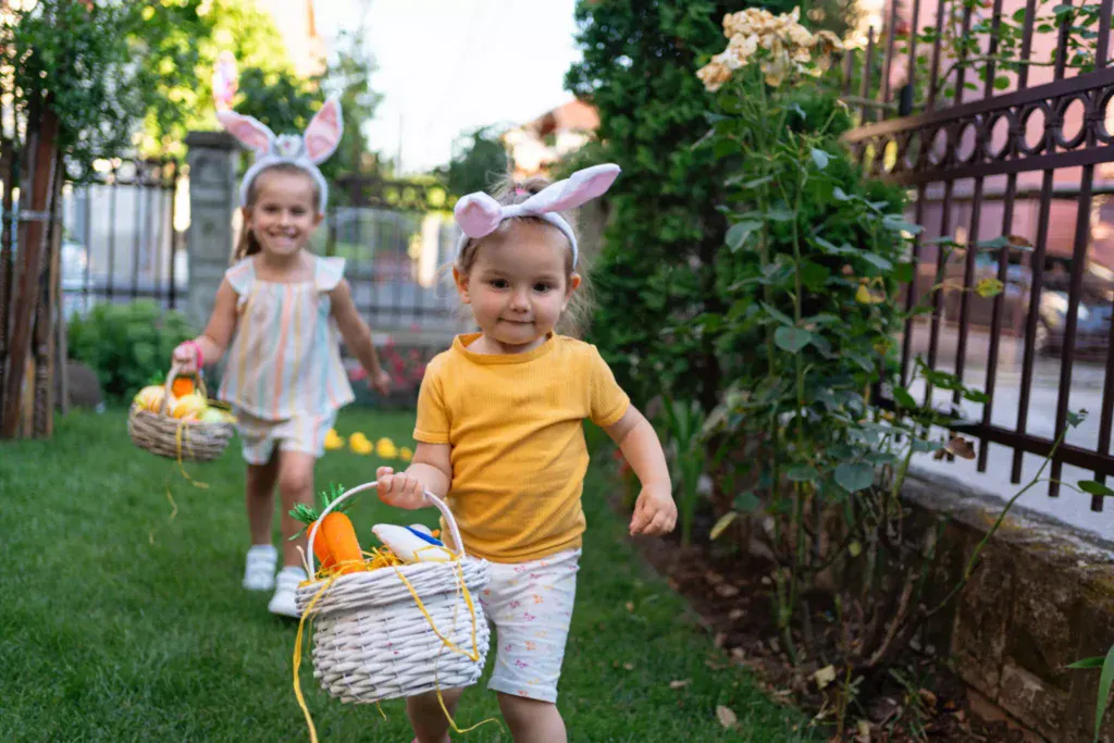 Two little girls participate in an Easter egg hunt.